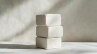 Stack of three white marshmallows on light background with soft shadows, minimalist food photography composition for confectionery and dessert concepts.