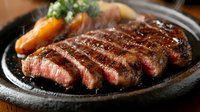 Grilled beef steak sliced and served on hot cast iron plate with vegetables. Juicy medium-rare meat with grill marks ready for restaurant menu or food blog.