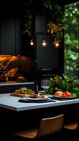 Modern dark kitchen interior with pendant lights and served dinner table featuring fresh food, wine glasses, and decorative greenery against black walls.