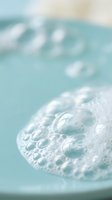 Clear water bubbles floating in turquoise pool with soft bokeh background creating refreshing summer atmosphere for wellness and relaxation concepts.