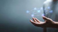 Mans hand holding a glowing digital network of connected nodes, representing blockchain, AI, and data technology concepts in a modern business setting.