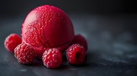 Red raspberry sorbet scoop on dark background with fresh ripe raspberries, macro food photography with selective focus and moody lighting.