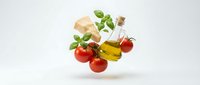 Fresh ingredients floating in air with cherry tomatoes, basil leaves, olive oil bottle and bread for cooking and culinary design on white background.