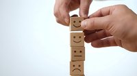 Hands stacking wooden blocks with emotion faces from sad to happy showing customer satisfaction rating and feedback concept for business improvement.