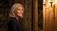 Elegant senior Caucasian businesswoman with silver hair in luxury hotel lobby interior with ornate mirror and warm lighting for corporate hospitality concepts.