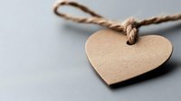 Minimalist heart-shaped paper tag with natural twine string on light background, romantic vintage style label for gifts and crafts.