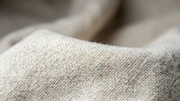Natural linen fabric texture with soft focus showing woven fibers and organic material surface for textile and fashion design projects.