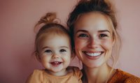Happy young Caucasian mother and toddler daughter smiling together in warm orange clothing against soft pink background for family lifestyle content.