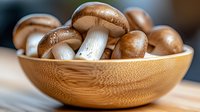 Fresh brown champignon mushrooms in wooden bamboo bowl on kitchen table, macro food photography with selective focus and natural lighting.