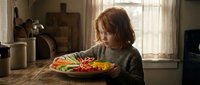 Young redhead woman enjoying healthy colorful salad meal at kitchen table during daytime for nutrition and wellness lifestyle content.