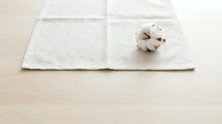 Natural cotton boll on white linen fabric showcasing organic textile materials and sustainable fashion concepts for eco-friendly design projects.