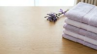 Stack of folded lavender towels with dried lavender flowers on wooden table, spa and home textile concept for wellness and relaxation design.