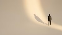 Man standing beside his shadow cast on beige wall, representing self-reflection, identity, and personal growth for motivational and business concepts.