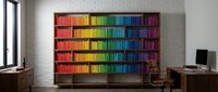 Rainbow colored books arranged by hue on wooden bookshelf in modern office interior with white brick wall and natural lighting for creative workspace design.