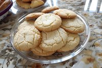 Homemade crinkle sugar cookies with distinctive cracked surface texture served on clear glass plate, fresh baked golden treats with crispy edges and soft centers.