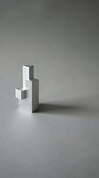 Stacked geometric concrete and white blocks arranged in ascending steps on neutral gray surface, showcasing modern minimalist architecture and design concepts.