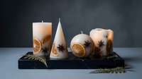 Decorative candles with dried citrus slices and star anise on black marble base, ideal for home decor, wellness, and seasonal styling projects.