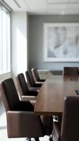 Modern corporate boardroom with leather chairs around wooden conference table in bright office space for business meetings.