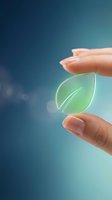 Human hands gently holding glowing green leaf symbol representing environmental protection, sustainability and eco-friendly business practices.