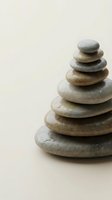 Zen stone tower stack with smooth river rocks balanced in pyramid formation on neutral beige background for meditation wellness spa therapy relaxation mindfulness.