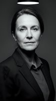 Middle-aged woman with dark hair wearing black blazer against dark background with glowing halo above head. Suitable for spirituality, religion, and faith-based projects.