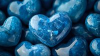 Shiny blue crystal hearts with glitter texture and sparkles arranged in romantic composition, macro photography showing detailed surface and reflections.
