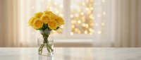 Yellow roses in glass vase on white table with warm bokeh lights creating cozy home interior atmosphere for romantic occasions and celebrations.