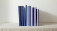 Row of purple and lavender books arranged by height on wooden shelf against neutral wall creating minimalist home decor display for interior design projects.
