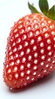 Fresh ripe strawberry with green leaves isolated on white background, close-up macro shot showing detailed texture and seeds for food and nutrition.
