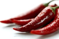 Fresh red chili peppers with water drops on white background, macro shot showing texture and glossy surface. For food and cooking concepts.