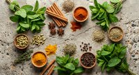 Fresh herbs and aromatic spices arranged on rustic wooden background for culinary cooking and seasoning recipes in kitchen preparation.