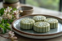 Traditional green tea matcha mooncakes with decorative patterns on ceramic plate, Asian dessert for Mid-Autumn Festival celebration and cultural dining.