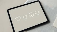 Digital tablet displaying minimalist line icons including heart, star, clock and message symbols on neutral beige screen for modern interface design projects.