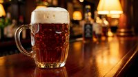 Fresh amber beer with foam head in traditional glass mug on wooden bar counter in cozy pub atmosphere with warm lighting for hospitality concepts.