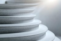 Stacked ceramic plates in soft gray tones create minimalist composition with gentle curves and textures, showcasing modern tableware design and dining essentials.