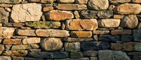 Ancient stone wall texture with weathered rocks and natural mortar joints for rustic architectural backgrounds and construction design projects.