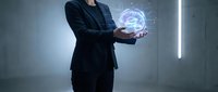 Professional businessman in dark suit holding glowing holographic brain with neural network connections in modern office environment for AI technology concepts.