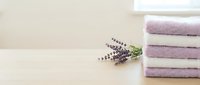 Stacked lavender and white towels with fresh lavender flowers on neutral background, spa and wellness concept for home decor and relaxation themes.
