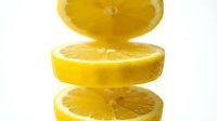 Three vibrant yellow lemon slices stacked vertically on a white background, showcasing fresh citrus texture for food and beverage projects.