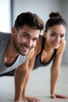 Young diverse couple doing plank exercise together at home, smiling while maintaining proper form during morning workout routine.
