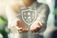 Insurance protection concept with white shield and icons floating above open palms, representing safety, security and risk management in business and personal life.