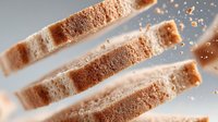 Fresh sliced bread with golden crust and soft crumb texture scattered with crumbs on neutral background for culinary and bakery concepts.