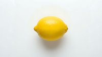 Fresh yellow lemon with textured skin on white background, suitable for food, beverage, and culinary design projects.