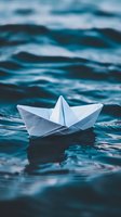 White paper boat floating on dark blue rippling water surface, creating gentle reflections and waves in moody atmospheric lighting.