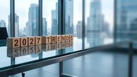 Wooden blocks spelling 2027 Trends on a glass table in a modern office with city skyline, symbolizing future business strategy and planning.
