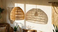 Woven rattan pendant lamps casting geometric shadows on a neutral wall, surrounded by potted plants and natural fiber decor, perfect for interior design and home styling projects.
