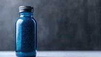 Sparkling blue glitter in glass mason jar against dark background, magical festive decoration for crafts and holiday projects.