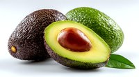 Fresh avocados on white background, one cut in half showing pit and creamy flesh, with green leaf, ideal for healthy eating concepts.