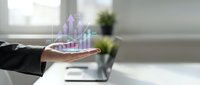 Young professional male in business attire holding holographic rising bar chart and financial growth data visualization above palm, representing digital analytics and investment success.