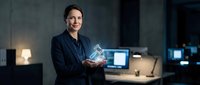 Middle-aged woman with dark hair, Caucasian ethnicity, wearing dark blazer, holding glowing digital hologram in modern office environment with computers and technology setup.